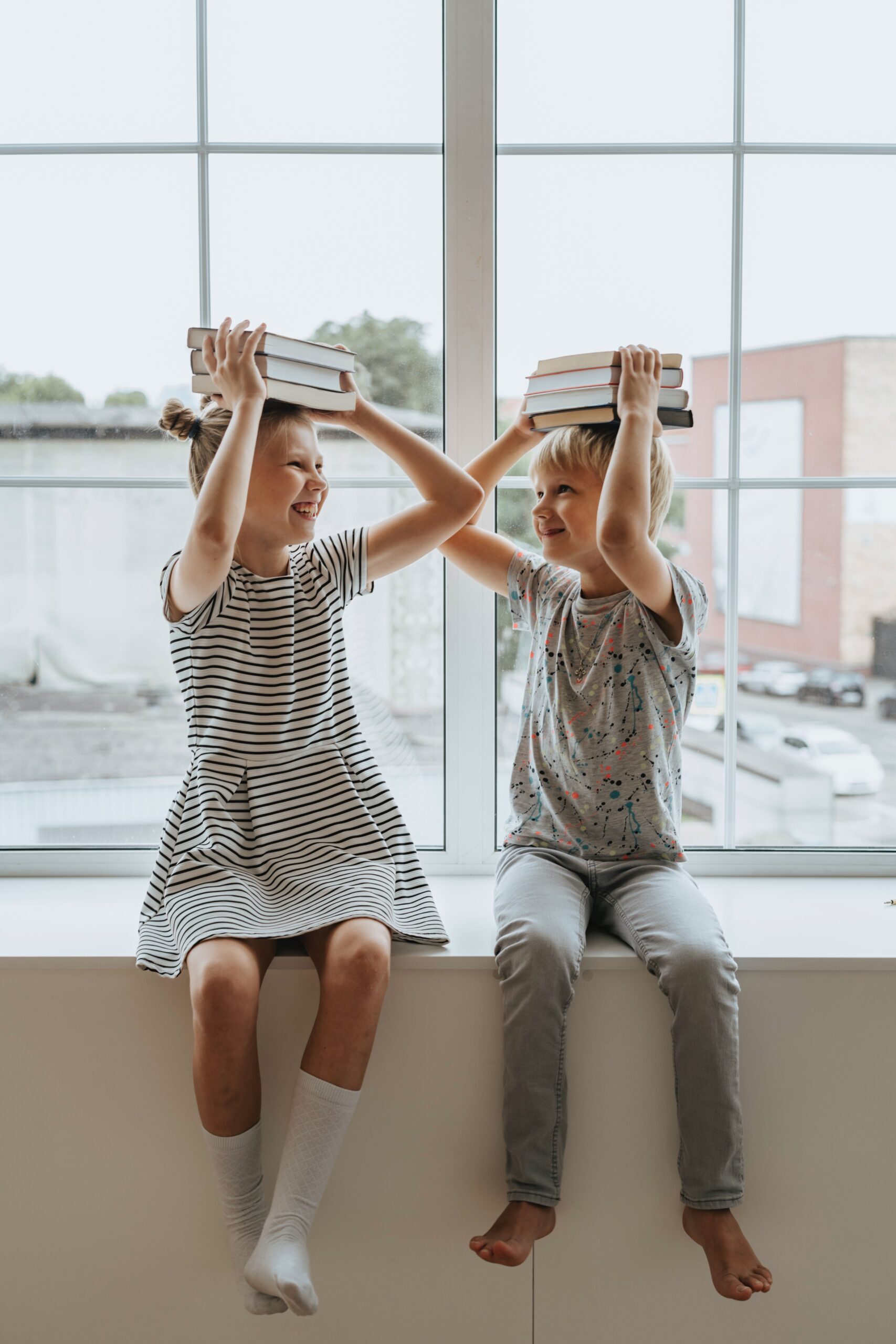 Speech therapy for kids involves play, as two children hold book stacks on their heads